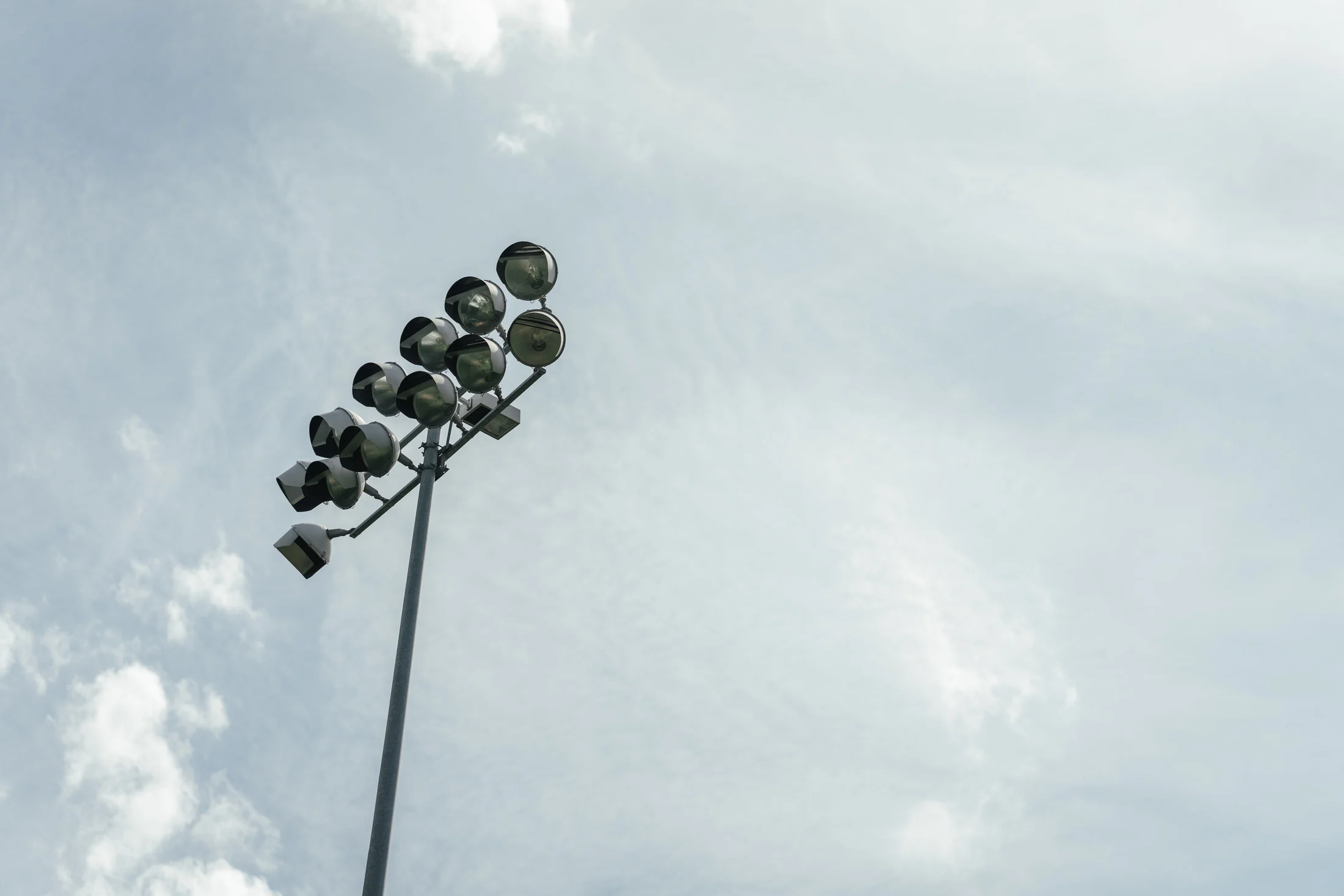 Baseball field lights against a bright sky